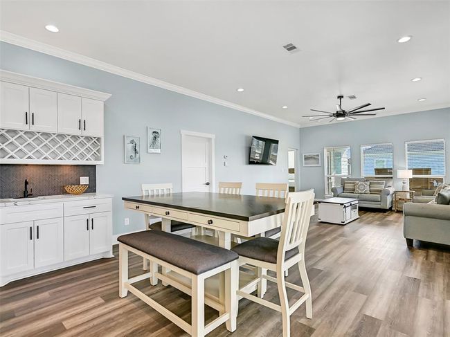 Gather to share a meal or work a puzzle in this cozy dining area with a built-in wet bar with a sink, cabinetry, and wine storage. | Image 10