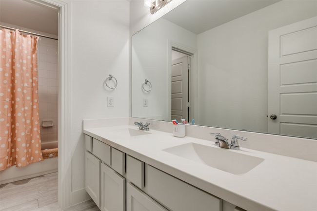 Bathroom featuring wood finished floors, shower / tub combo with curtain, a sink, and double vanity | Image 16
