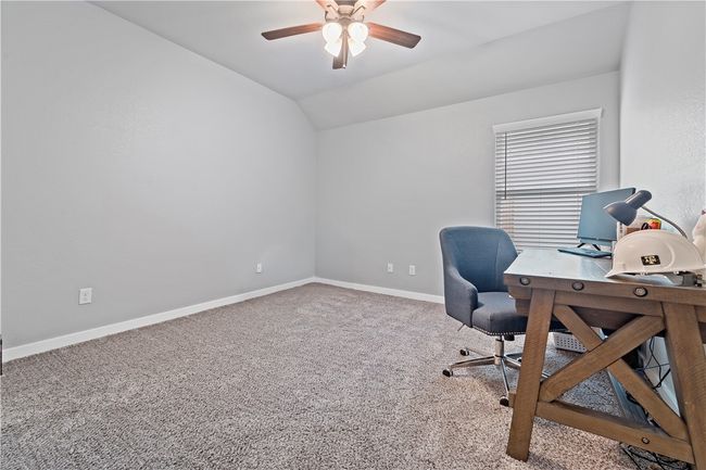 Carpeted home office featuring a ceiling fan, baseboards, and lofted ceiling | Image 12