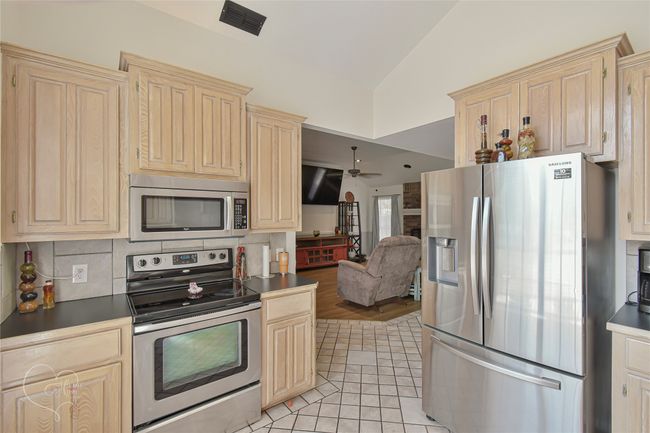Kitchen with appliances with stainless steel finishes, lofted ceiling, decorative backsplash, open floor plan, and ceiling fan | Image 35