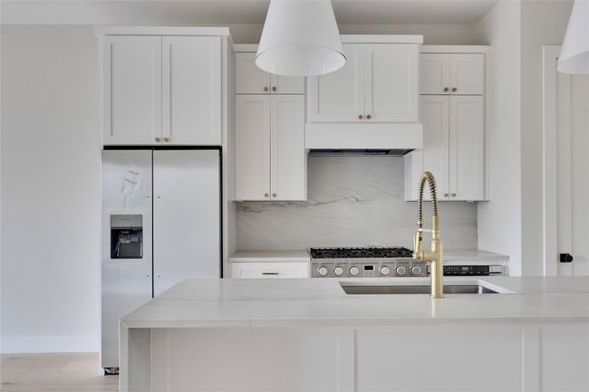 Kitchen featuring exhaust hood, a sink, white refrigerator with ice dispenser, tasteful backsplash, and white cabinets | Image 23