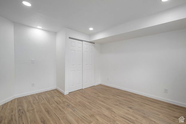 Basement bedroom with light wood-type flooring, a closet, baseboards, and recessed lighting | Image 23