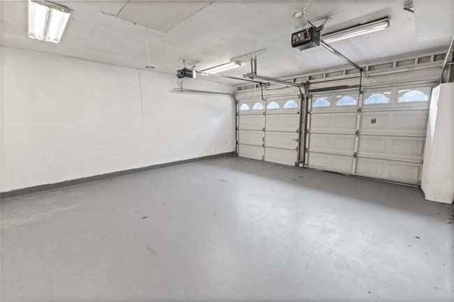 Garage featuring a garage door opener and baseboards | Image 26