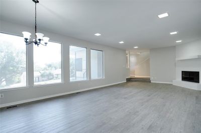 Unfurnished living room featuring a notable chandelier, hardwood / wood-style flooring, and plenty of natural light | Image 2