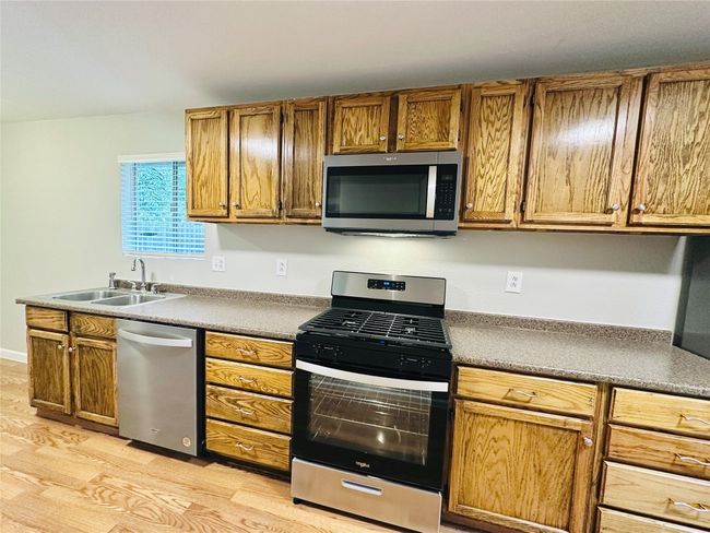 Kitchen featuring appliances with stainless steel finishes, light wood-style flooring, and brown cabinetry | Image 7