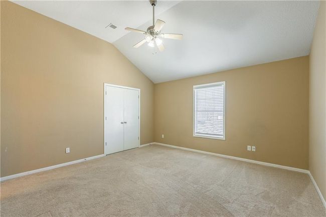 Empty room with a ceiling fan, visible vents, baseboards, high vaulted ceiling, and light carpet | Image 8