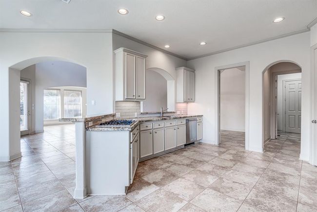 Updated steel appliances throughout including Jenn Air gas cook top. Beautiful tile back splash and granite counter tops. Recessed and under mount lighting and crown molding. This beautiful dream kitchen can be yours! | Image 18