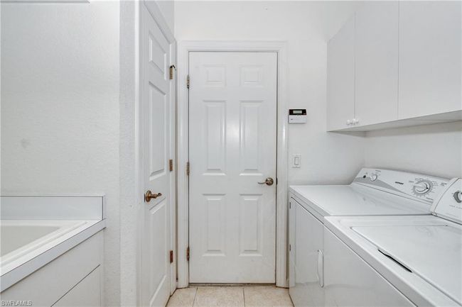 Laundry room with light tile patterned floors, washer and clothes dryer, and cabinets | Image 10
