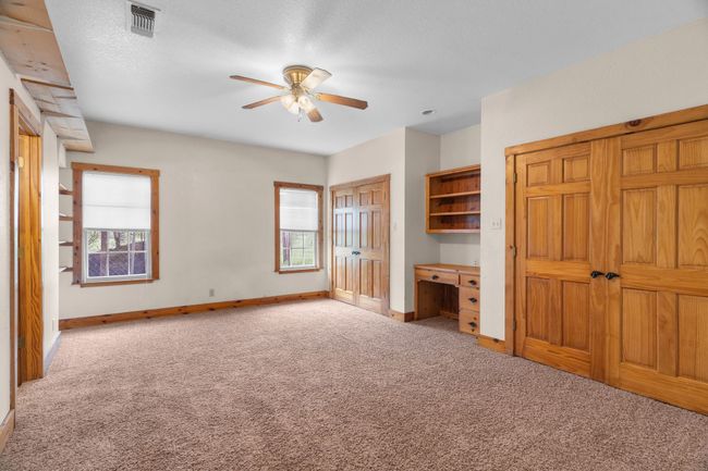 Unfurnished bedroom with carpet flooring, visible vents, multiple windows, and built in desk | Image 24