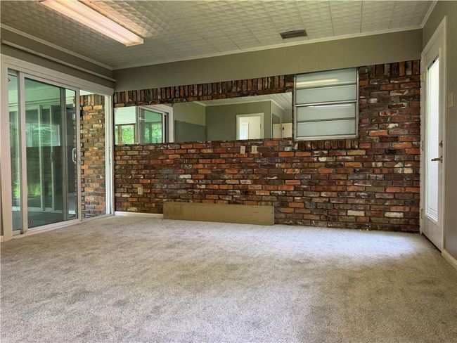 Unfurnished room featuring brick wall, carpet flooring, and crown molding | Image 16