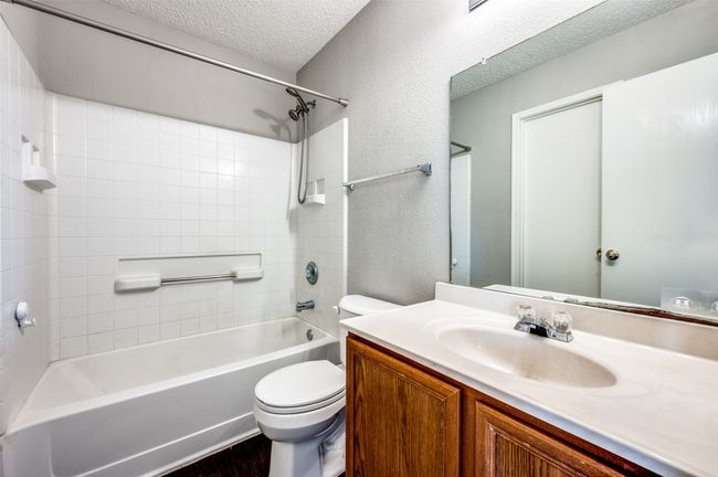 Bathroom featuring toilet, vanity, shower / bath combination, a textured ceiling, and wood finished floors | Image 18
