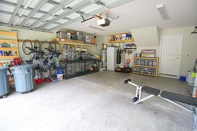 Garage with a workshop area, a garage door opener, and water heater | Image 29