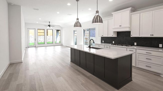 Kitchen with white cabinets, backsplash, a center island with sink, decorative light fixtures, and recessed lighting | Image 15