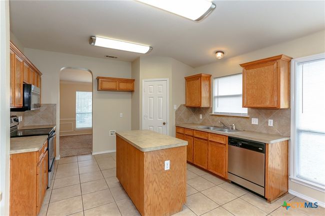 Kitchen showing the island, sink, area for refrigerator, and pantry. | Image 13