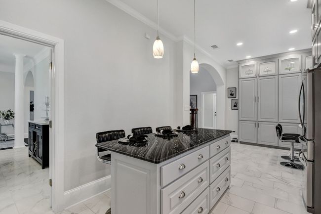Kitchen featuring light marble finish floors, ornamental molding, arched walkways, freestanding refrigerator, and recessed lighting | Image 16