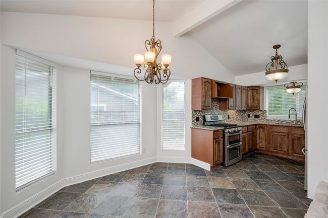 Kitchen featuring a sink, stone tile flooring, a notable chandelier, double oven range, and baseboards | Image 11