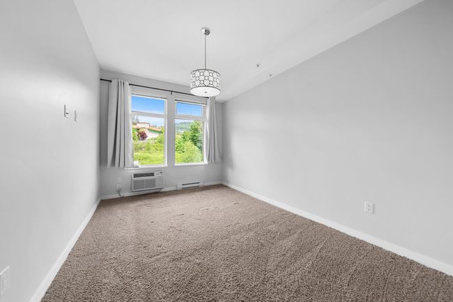 Empty room with carpet flooring, baseboards, a baseboard radiator, and an AC wall unit | Image 29