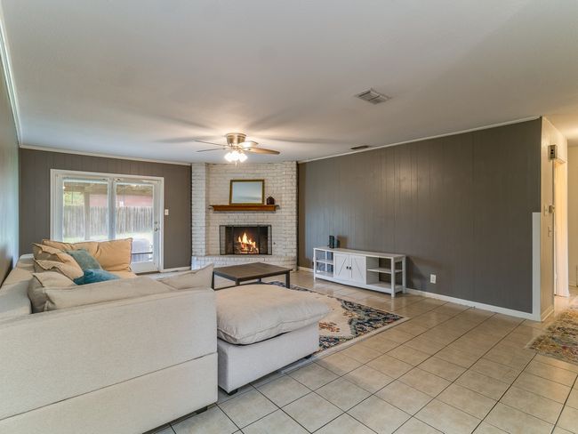 Living room featuring ceiling fan, light tile patterned floors, a fireplace, and crown molding | Image 5