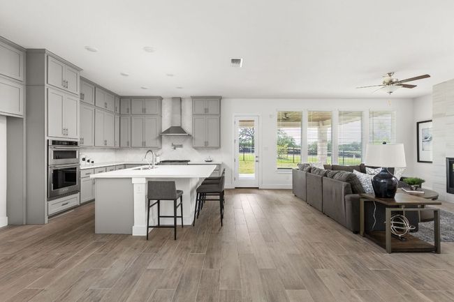 Kitchen featuring wall chimney exhaust hood, gray cabinets, double oven, and light countertops | Image 11