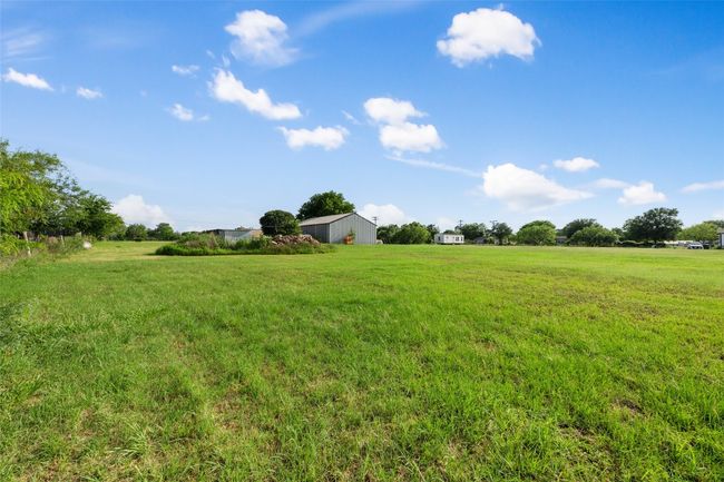 View of grassy yard featuring a pole building, a rural view, and an outbuilding | Image 6