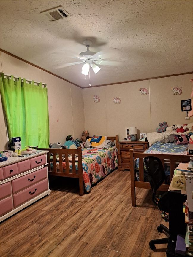 Bedroom with crown molding, a textured ceiling, wood finished floors, and ceiling fan | Image 11