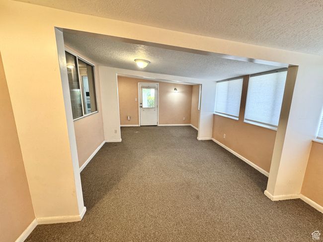 Carpeted spare room featuring a textured ceiling and baseboards | Image 23