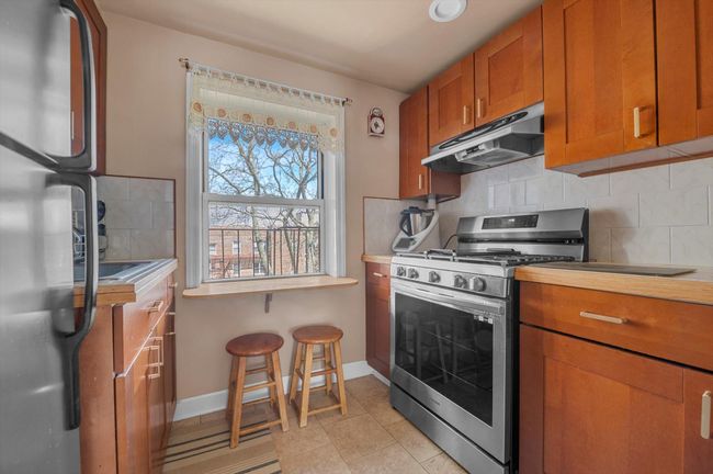 Kitchen with brown cabinets, decorative backsplash, appliances with stainless steel finishes, baseboards, and under cabinet range hood | Image 6