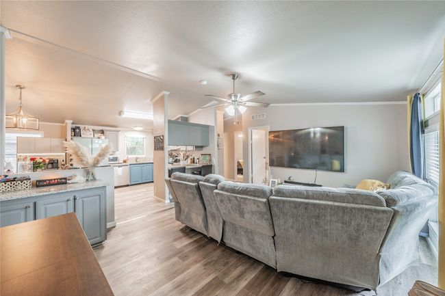 Living room with a ceiling fan, light wood-style flooring, vaulted ceiling, and crown molding | Image 7