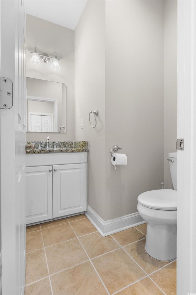 Half bath with tile patterned flooring, vanity, toilet, and baseboards | Image 10