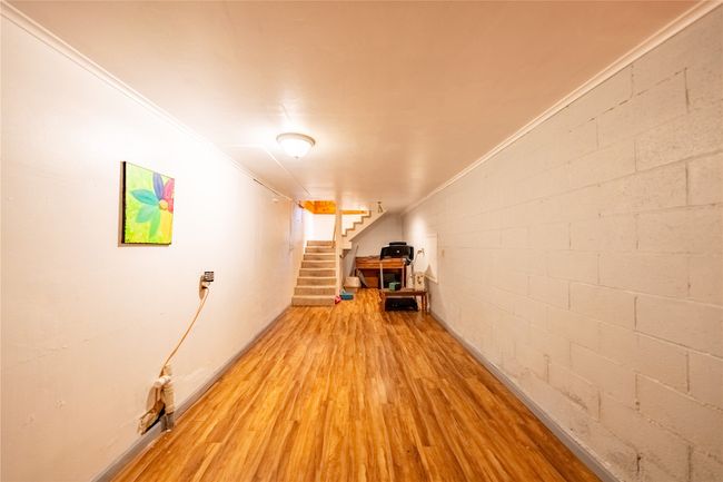 Finished below grade area featuring wood finished floors, stairway, and ornamental molding | Image 36