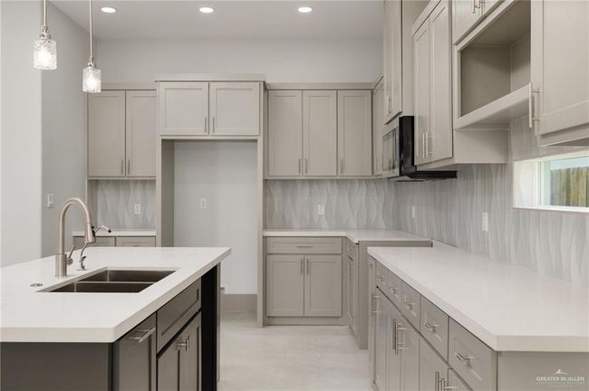 Kitchen with gray cabinets, a kitchen island with sink, recessed lighting, backsplash, and decorative light fixtures | Image 8