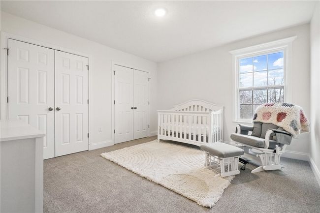 Serene and spacious bedroom with soft carpeting, neutral tones, and a large window providing peaceful natural light. Features double closets for ample storage and a flexible layout perfect for a nursery, guest room, or additional sleeping space. | Image 27