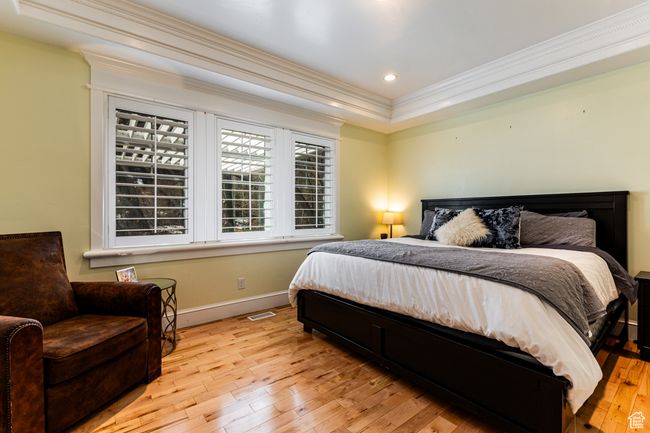Bedroom featuring crown molding, baseboards, visible vents, light wood-style floors, and recessed lighting | Image 12