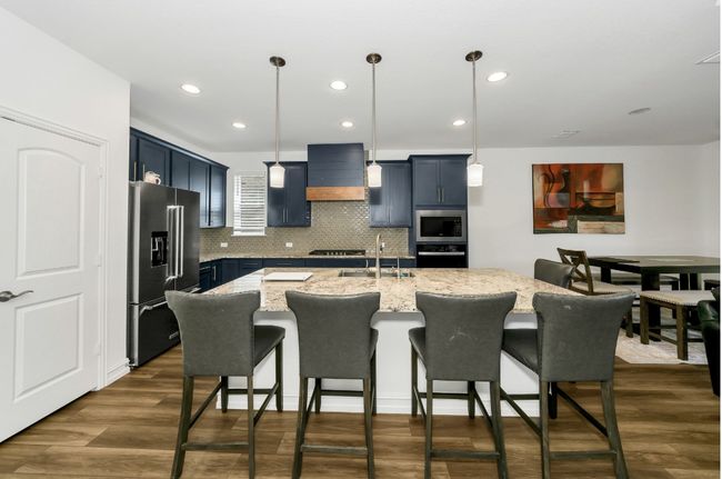 Kitchen with premium range hood, a breakfast bar, stainless steel appliances, and a sink | Image 9