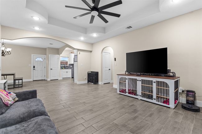 Living area featuring arched walkways, a tray ceiling, ceiling fan, recessed lighting, and wood finished floors | Image 12