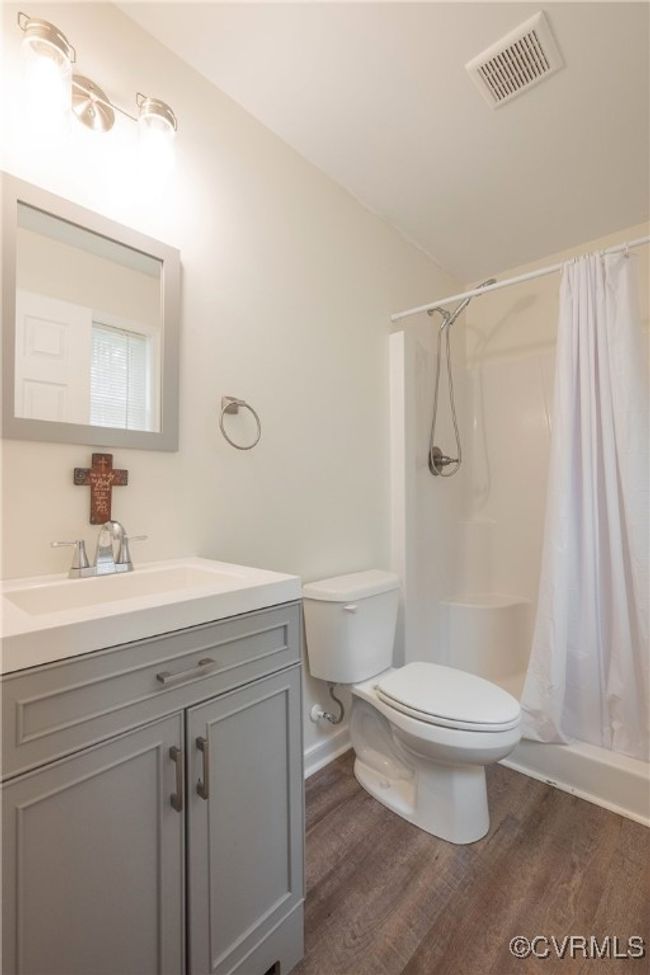 Bathroom featuring visible vents, wood finished floors, toilet, and curtained shower | Image 28