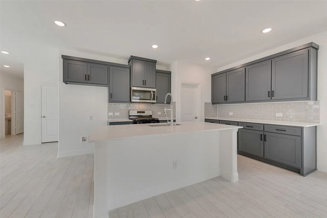 Kitchen featuring appliances with stainless steel finishes, a sink, light countertops, backsplash, and an island with sink | Image 4