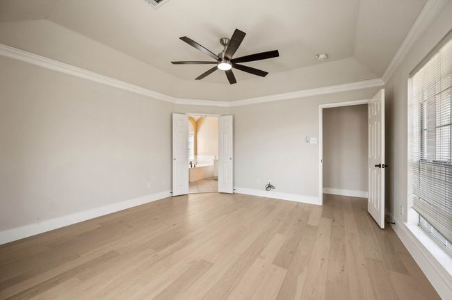 Unfurnished bedroom featuring baseboards, light wood-style flooring, crown molding, and a raised ceiling | Image 21