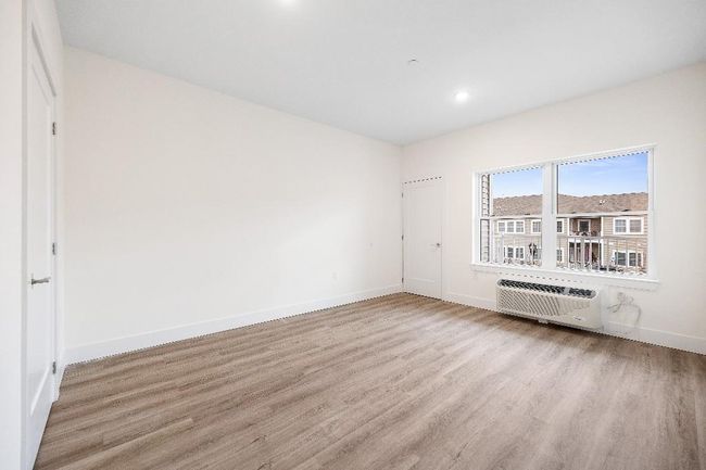 Empty room featuring wood finished floors, an AC wall unit, baseboards, and recessed lighting | Image 41