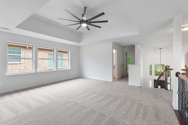 Unfurnished living room with attic access, a tray ceiling, a ceiling fan, visible vents, and carpet floors | Image 25