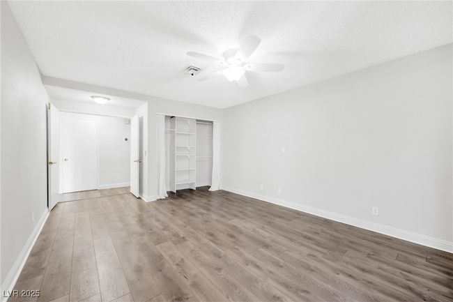 Unfurnished bedroom featuring wood finished floors, a ceiling fan, visible vents, and baseboards | Image 12