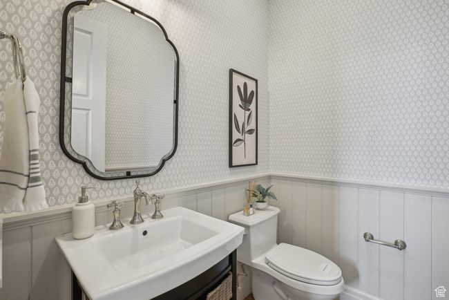 Bathroom with a wainscoted wall, a sink, toilet, and wallpapered walls | Image 20