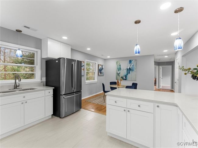 Kitchen with light countertops, hanging light fixtures, freestanding refrigerator, white cabinets, and a sink | Image 20