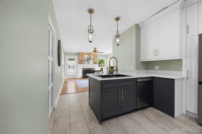 Kitchen with stainless steel dishwasher, a peninsula, open floor plan, a ceiling fan, and white cabinetry | Image 11