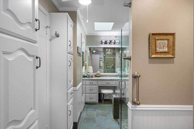 Bathroom with ceiling fan, a stall shower, ornamental molding, vanity, and a skylight | Image 20