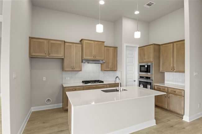 Kitchen featuring stainless steel appliances, a sink, under cabinet range hood, a high ceiling, and tasteful backsplash | Image 19