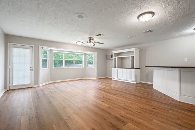 Spare room featuring wood finished floors, a ceiling fan, a textured ceiling, baseboards, and a wall unit AC | Image 8