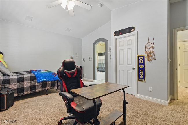 Bedroom featuring arched walkways, vaulted ceiling, baseboards, light colored carpet, and ceiling fan | Image 29
