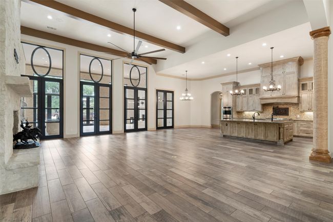 Unfurnished living room featuring dark wood-style flooring, a sink, beam ceiling, ceiling fan with notable chandelier, and recessed lighting | Image 9