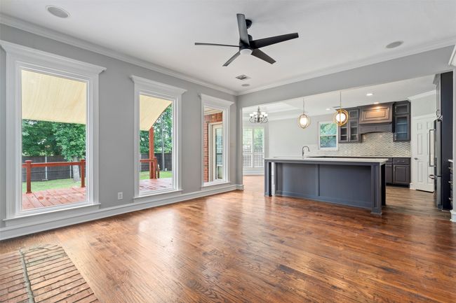 Kitchen featuring dark wood-type flooring, freestanding refrigerator, a chandelier, glass insert cabinets, and an island with sink | Image 5